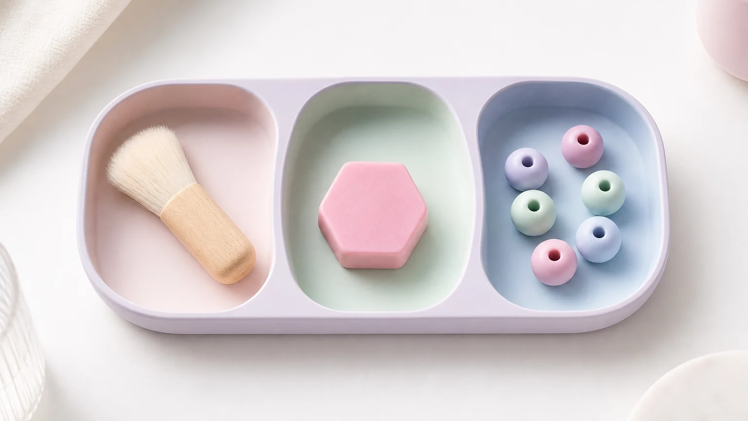 A soft brush, one pastel wax shape, and large beads arranged in three sound-tray compartments.